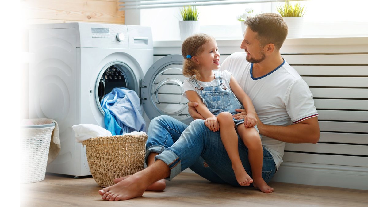 A family beside a washing machine used as a decorative Oxisson home-care image
